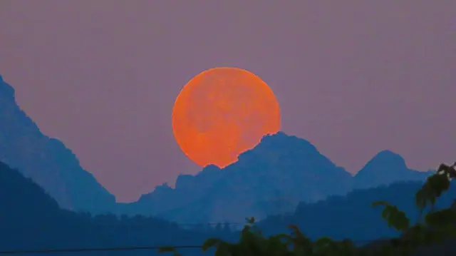 Spektakulär geht der Vollmond hinter den Bergen unter.