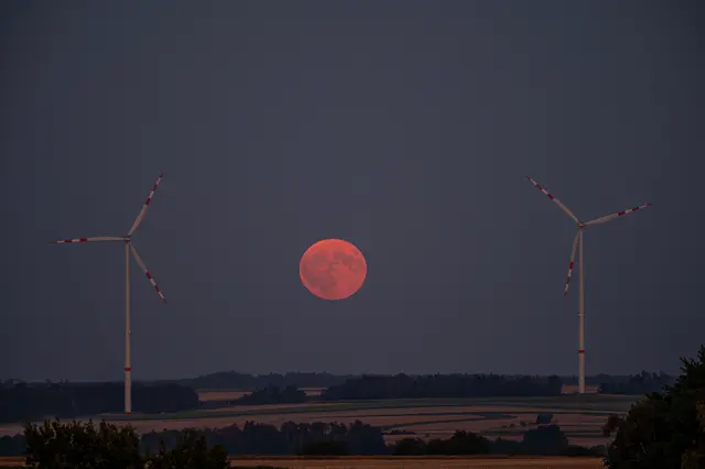 Zwei Windräder des Windparks Japons flankieren den aufgehenden Heumond. 