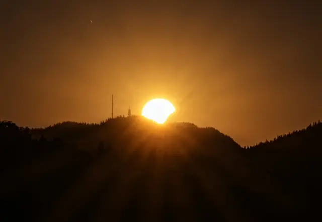 Von Kirchberg am Wechsel aus gesehen gehen am 12. August Sonne und Mond gemeinsam hinter dem Sonnwendstein unter. 
