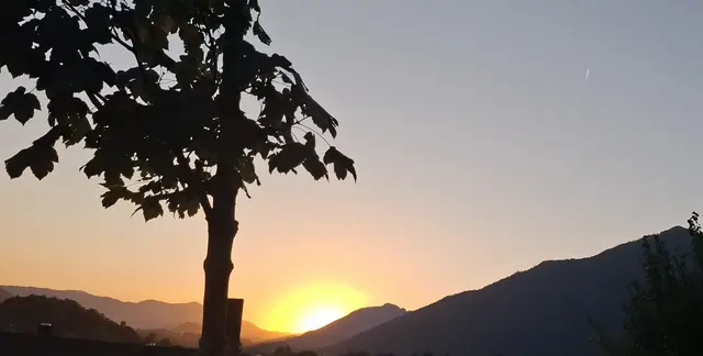 Sonne geht hinter Bergen unter.